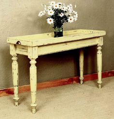 a vase with daisies sits on an old table