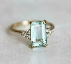 an emerald and diamond ring sitting on top of a table