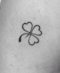 a four leaf clover tattoo on the back of a woman's left arm,