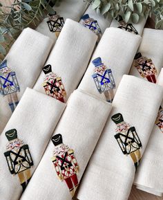 six embroidered napkins with designs on them sitting on a table next to a potted plant