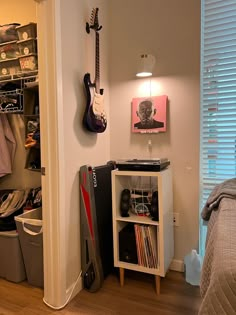 a bedroom with a bed, guitar and other items on the shelf next to it