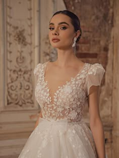 a woman in a wedding dress standing next to a wall with ornate carvings on it