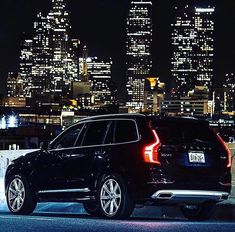 a black suv parked in front of a city at night