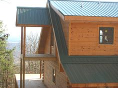 a wooden house with metal roofing on top of a hill