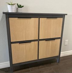 a wooden cabinet with four drawers and a potted plant sitting on top of it