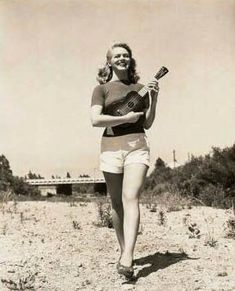 an old photo of a woman walking on the beach with a paddle in her hand