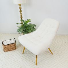 a white chair sitting next to a lamp on top of a floor near a basket