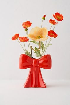 a red vase filled with flowers on top of a table