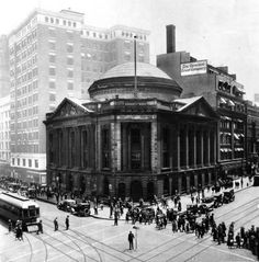 an old black and white photo of people on the street in front of a building