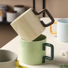 three mugs stacked on top of each other with one being held in the air