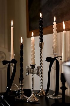 candles are lit on a table with black and white ribbons in front of the candle holders