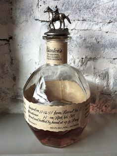 a glass bottle filled with liquid sitting next to a brick wall