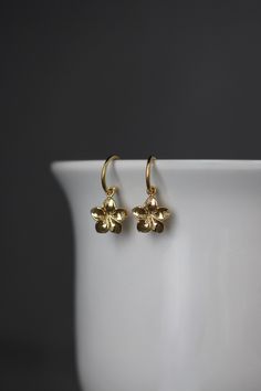 "Sweet and delicate 18k gold vermeil Plumeria flower charms dangle from 24k gold vermeil post hoops. The perfect go-to-earrings for any occasion and any age. Gold flower charms: 11x11mm Total length of earrings: almost 1\" All gold is gold vermeil, gold plating over sterling silver. A matching necklace is available... www.etsy.com/listing/1574987377/plumeria-flower-necklace As the owner, maker, designer, and curator of this shop, I take great pride in providing you with jewelry that you will lov Gold Flower Charm Earrings In 14k Gold, Dainty Hoop Earrings With Flower Charm, Delicate Flower Charm Hoop Earrings, Gold Hoop Earrings With Flower Charm For Gift, Yellow Gold Flower Earrings With Charm, 14k Gold Earrings With Flower Charm For Gift, Delicate Gold Flower Charm Earrings, Yellow Gold Flower Charm Earrings, Gold Flower-shaped Earrings With Flower Charm