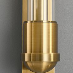 a close up of a wall mounted light on a gray wall with silver and gold trim