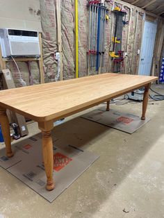 a wooden table sitting on top of a hard wood floor next to a pile of tools