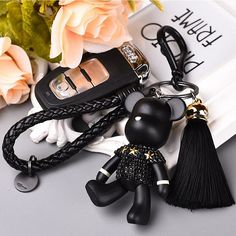 a key chain with a black cat on it next to flowers and a cell phone