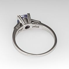 This alluring ring is centered with a no heat Tanzanian sapphire weighing 1.75 carats that we sourced and set in an elegant vintage platinum mounting. The shoulders of the ring are each accented with two (2), bead set, old European/single cut diamonds. The ring measures 7.0mm at the top, rises 7.2mm above the finger, tapering to 1.6mm wide and 1.2mm thick at the base of the shank. This ring is currently a size 9.75. Classic Sapphire Tanzanite Solitaire Ring, Classic Tanzanite Solitaire Sapphire Ring, Purple Sapphire Ring With Prong Setting For Formal Occasions, Elegant Tanzanite Wedding Ring With Prong Setting, Elegant Tanzanite Promise Ring, Tanzanite Birthstone Ring With Center Stone For Promise, Elegant Tanzanite Birthstone Ring For Promise, Classic Purple Birthstone Ring With Center Stone, Tanzanite Birthstone Ring For Promise