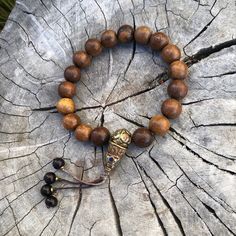 Approximately 13mm phoenix tail wood beads on brown cord wrist mala bracelet  Fits sizes 7 1/2 to 8 There is a small variation in regards to inlay brass bead. Wooden beads are approximately 12mm Brown Wooden Beaded Bracelets With 8mm Beads, Spiritual Natural Wood Beaded Bracelets, Traditional Brown Beaded Bracelets With Large Beads, Traditional Brown Beaded Bracelet With Large Beads, Spiritual Brown Bracelets With Wooden Beads, Brown Spiritual Bracelets With Large Beads, Spiritual Brown Bracelets With Large Beads, Traditional Wood Bracelets With Round Beads, Traditional Wooden Bracelets With Round Beads