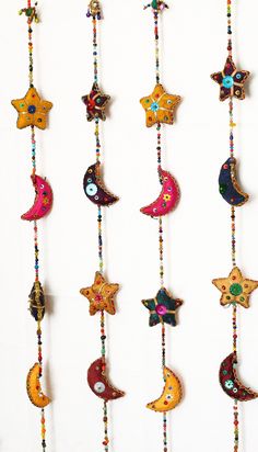 several colorful stars and crescents hanging from strings on a white wall with beaded beads