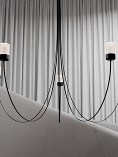 three lights that are hanging from the ceiling in a living room with curtains behind them