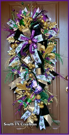 a purple and green wreath with gold bells on the front door for christmas or new year's eve