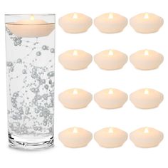 a glass filled with water and lit candles next to it's side, surrounded by smaller ones