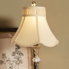 a lamp that is on top of a table next to a picture frame with flowers