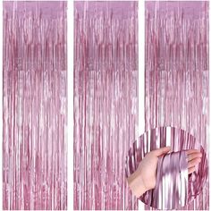 the pink curtain is being held up by someone's hand