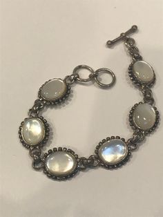 "Thiis is a beautiful, vintage, genuine, handmade Mother of Pearl and sterling silver bracelet that is adjustable and can be worn at either 7 inches or 7 1/2 inches. The bracelet is 5/8\" in width and features 6 Mother of Pearl links that measure about 3/4\" by 5/8\" each. The Mother of Pearls are set in polished sterling silver bezels with sterling silver beading around them. The MOP is so pretty, almost has the look of a Cat's Eye. The bracelet is stamped 925 and weighs about 22.1 grams. Gorgeous bracelet that is perfect for a bride to be or for wedding jewelry. See pictures for details.here Please note: This listing is for the bracelet only. The earrings and pendant seen in the last photo are being sold separately in my shop here: EARRINGS https://etsy.me/3CqwCwj PENDANT https://etsy.me Antique Sterling Silver Adjustable Bracelet, Adjustable Vintage Sterling Silver Bracelet, Handmade Oval Sterling Silver Bracelet In Vintage Style, Adjustable Sterling Silver Bohemian Bracelet, Adjustable Vintage Bracelets Stamped 925, Vintage Adjustable Sterling Silver Bracelet, Vintage Adjustable Sterling Silver Bracelet Stamped 925, Adjustable Vintage Stamped 925 Bracelets, Vintage Sterling Silver Bracelet Stamped 925