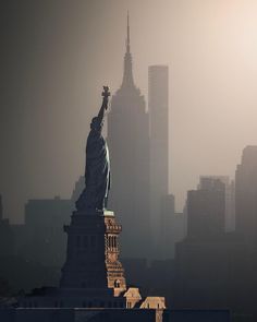 the statue of liberty in new york city is silhouetted against an overcast sky