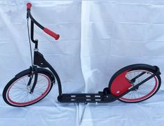 a red and black scooter on a white background with a curtain behind it