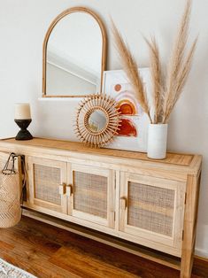 a white vase sitting on top of a wooden cabinet next to a mirror and lamp