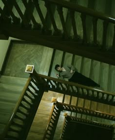 a man standing on top of a stair case next to a wooden wall and stairs