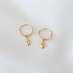 Sweet and cute, these are a pair of small huggie earrings with a dangling gold heart charm. All materials are 14K gold filled and are tarnish-resistant, water-resistant, and hypoallergenic. Hoop measures 12mm in diameter while the heart measures 4 mm in diameter. The heart charm is single sided with a hollow back which makes it very lightweight and comfortable for everyday wear. To put them on, don't pull the hoop apart, instead bend them towards opposite sides like shown in the photo. Happy sho Hypoallergenic Dangle Cartilage Earrings As Gift, Gift Dangle Cartilage Earrings, Single 14k Gold Filled Huggie Earring For Gift, Yellow Gold Dangle Hoop Earrings As Gift, Cute Hypoallergenic Round Hoop Earrings, Hypoallergenic Huggie Earrings Gift, 14k Gold Filled Cartilage Earrings As Gift, 14k Gold Filled Cartilage Earrings For Gift, 14k Gold Filled Drop Huggie Earrings As A Gift