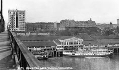 an old black and white photo of boats docked at a pier in the middle of a city