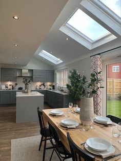 a dining room table with place settings in front of the kitchen and an open skylight