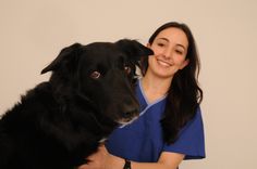 a woman in scrubs hugging a black dog