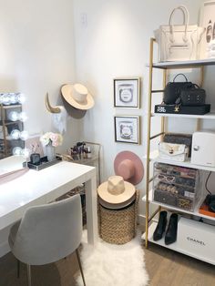 a white desk and chair in a room with hats on the shelves, purses and other items