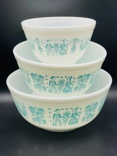 three blue and white bowls stacked on top of each other in front of a black background