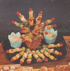 a table topped with lots of food on top of a black tray covered in fruit