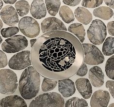 a metal plate with a turtle on it sitting on top of some rocks and pebbles