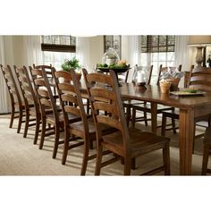 a dining room table with many chairs in front of it and a vase on top of the table