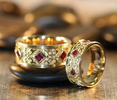 two gold wedding rings with rubles on top of each other sitting on a table