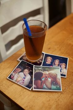 a glass filled with liquid sitting on top of a wooden table next to four polaroid pictures