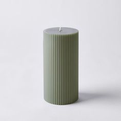 a green candle sitting on top of a white table