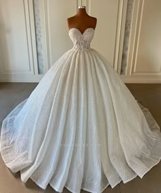 a white ball gown on a mannequin stand in front of a wall and door