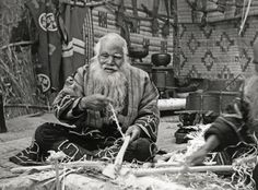 an old black and white photo of a man with a long beard sitting on the ground