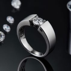 an engagement ring with three diamonds on the side and one diamond in the middle, surrounded by other jewelry items