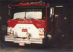 an old red and white fire truck parked in a garage