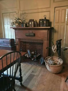 an old fashioned fireplace in a room with wooden flooring and walls painted white, next to a basket full of clutter